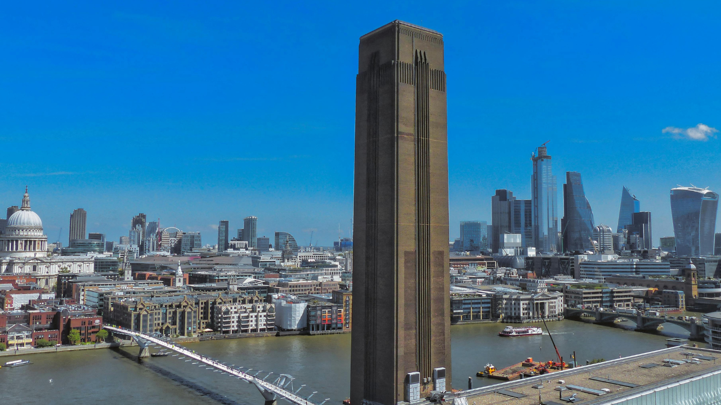 London skyline with Tate Modern in foreground and St Pauls and the City financial district in the background. Sky is bright blue